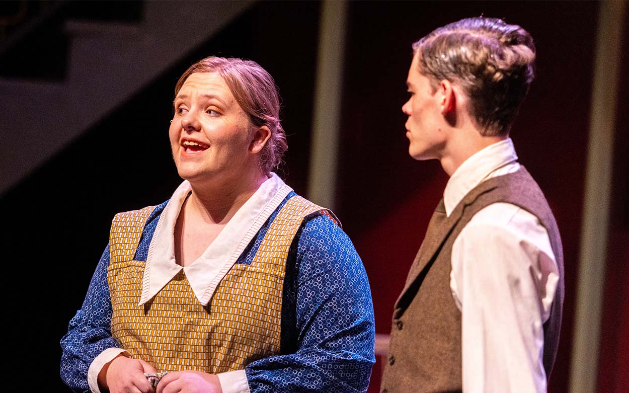 A woman singing as a man looks at her.