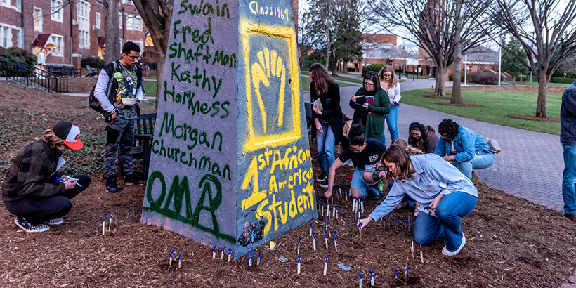 Students plant stakes in the ground that bear the names of enslaved people