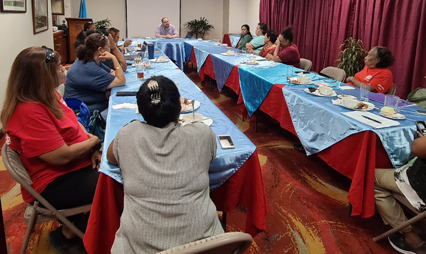 Chad Morris presents information at a conference to several health professionals seated around two long tables