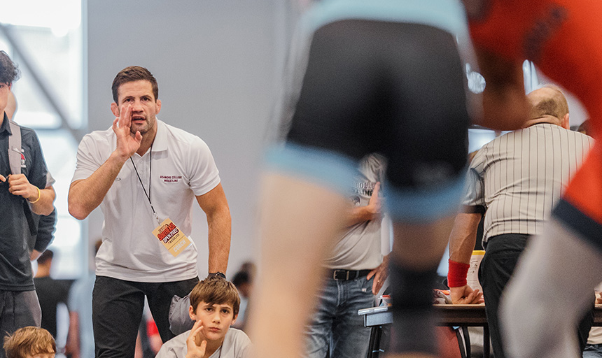 Coach Yetzer leans forward to offer advice to an athlete during a match