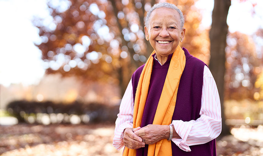 Nikki Giovanni stands outside with trees behind her