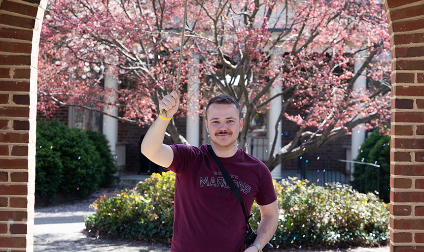 George Kendall smiles for a photo at the campus quad bell tower