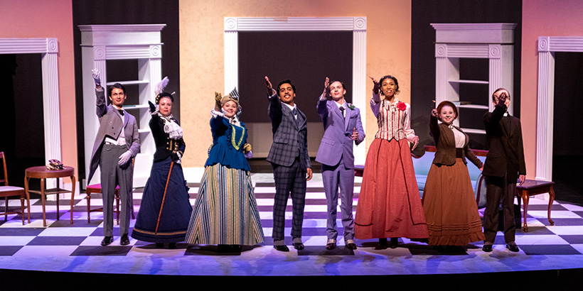 The cast stand next to one another onstage and gesture during a curtain call