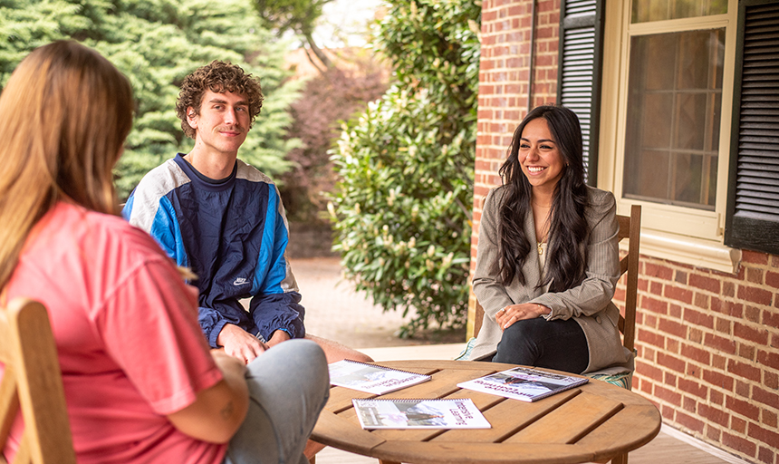 Assistant Director of Admissions Janny Alvarado meets with students on the Roselawn porch. Alvarado leads the school's Hispanic recruitment efforts.