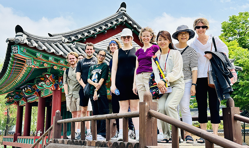 Students and professors stand in front of historic Korean building