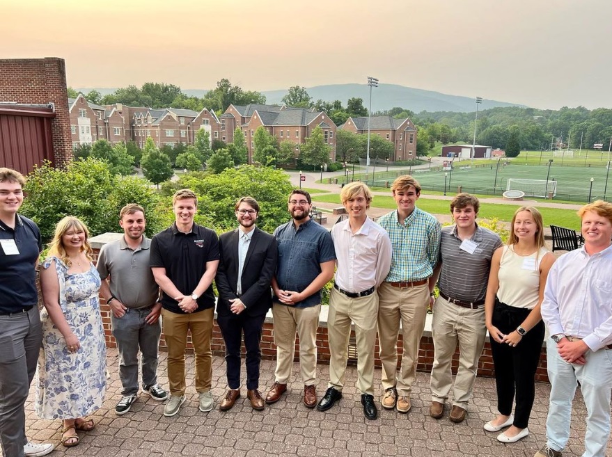 Students smile for a group photo on Sutton Terrace with a view of the mountains in the background