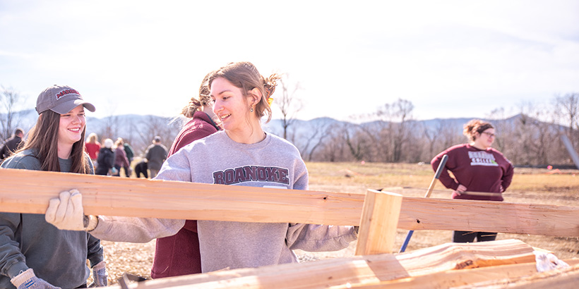 Multiple students put wooden fencing planks in place