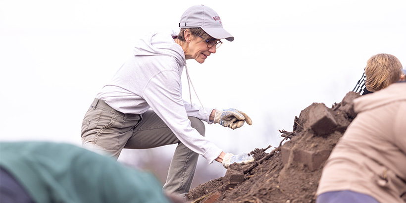 Reverend Kelly Shushok climbs a mountain of mulch