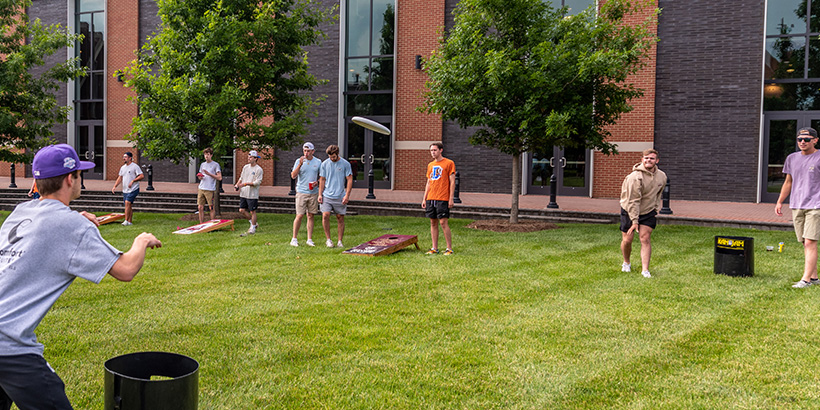 A frisbee flies through the air between two students playing the tailgating game Kan Jam