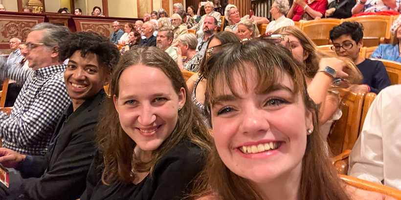 Students smile for a selfie in a well-appointed live performance theater