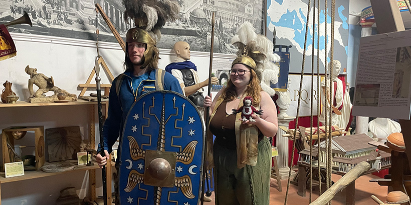 Two students dressed as Roman gladiators stand at attention while posing for a photo