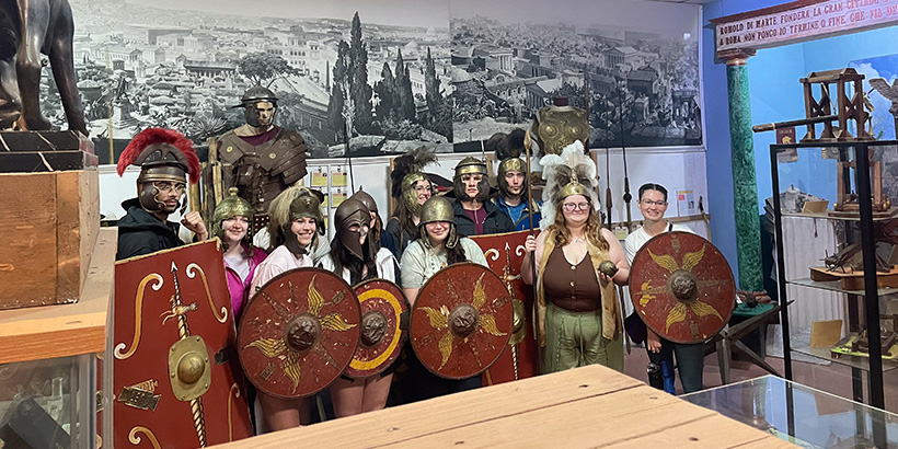 A dozen or so students dressed as Roman gladiators pose for a group photo