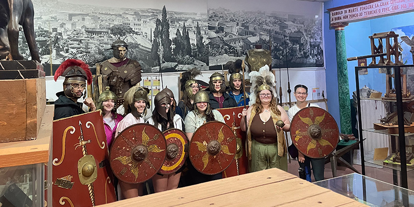 A dozen or so students dressed as Roman gladiators pose for a group photo