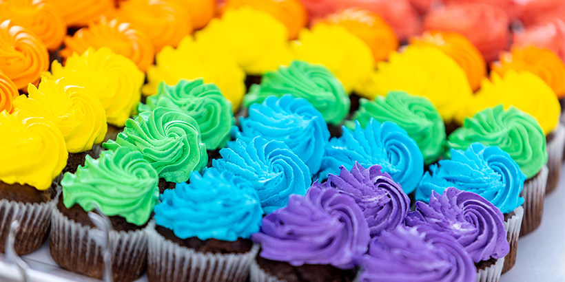 A tray of rainbow-hued cupcakes is set out for festival goers
