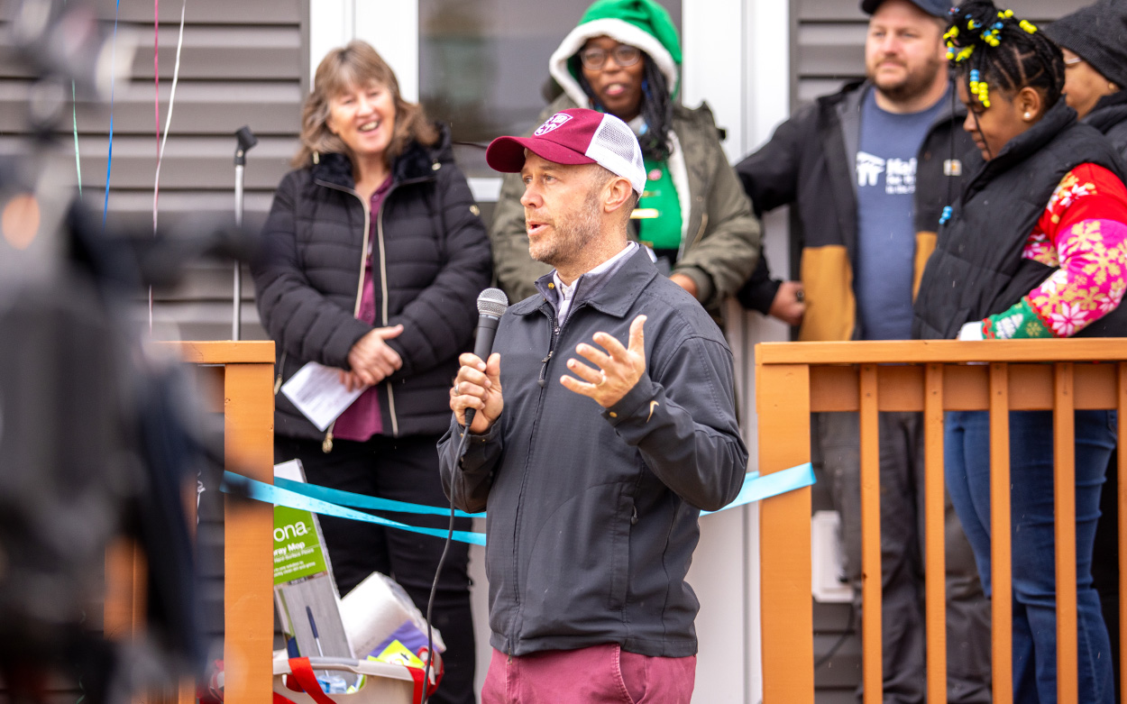 Chaplain Bowen, wearing a Roanoke College baseball cap, addresses a smiling crowd.