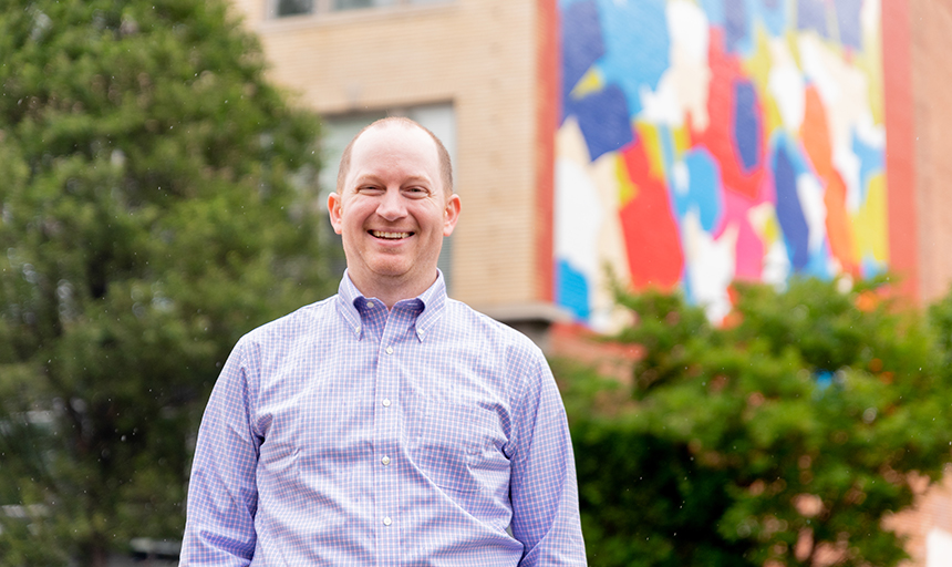 Peter "Reyn" Holden '12 poses for a photo with the Dorothy Gillespie mural in the background. Holden and his wife, Maria (Carino) Holden '14 supported the restoration of the mural in downtown Roanoke.