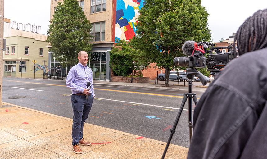 Reyn Holden '12 talks to a local news crew at the rededication of the Gillespie mural in Roanoke on May 15, 2023.