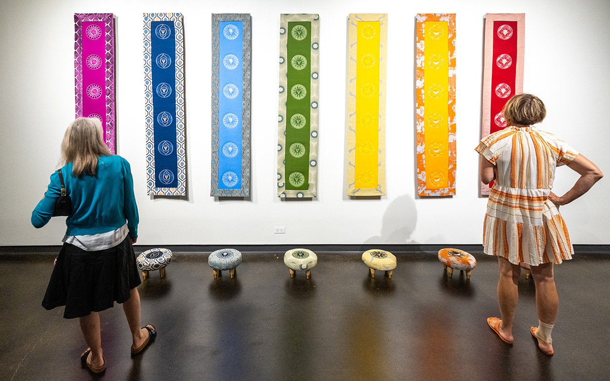 Visitors look at vivid, multi-colored panels representing body chakras