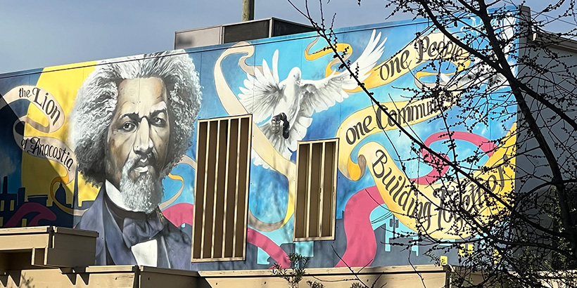 An outdoor mural in D.C. featuring the words One People, One Community, Building Together