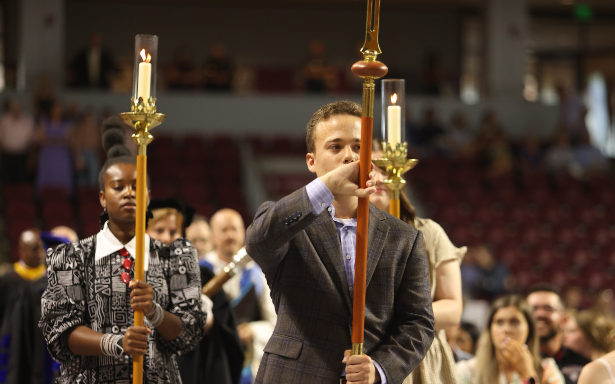 Students lead the starting procession carrying large ceremonial torches and a crucifix
