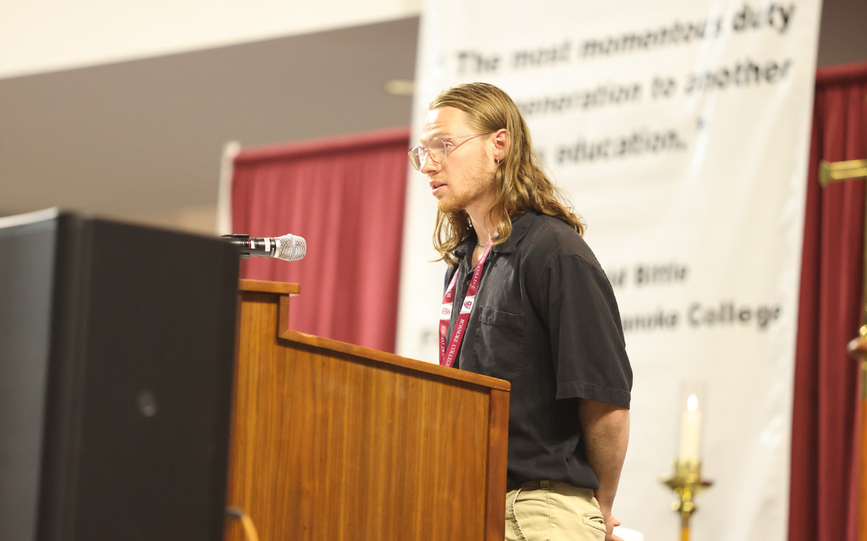 A student wearing a polo shirt offers a reading of the gospel from the stage's podium