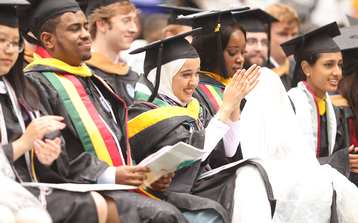 A student smiles and claps in the audience