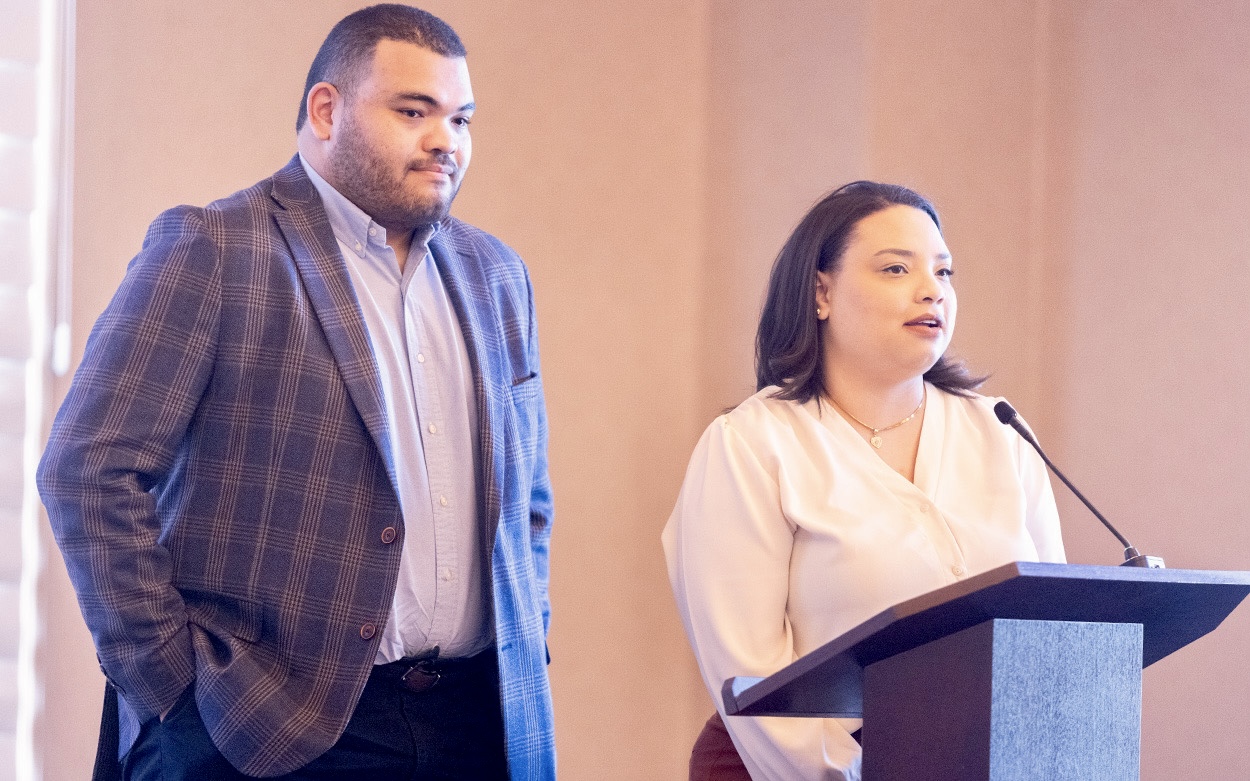 Two people address the audience from the stage