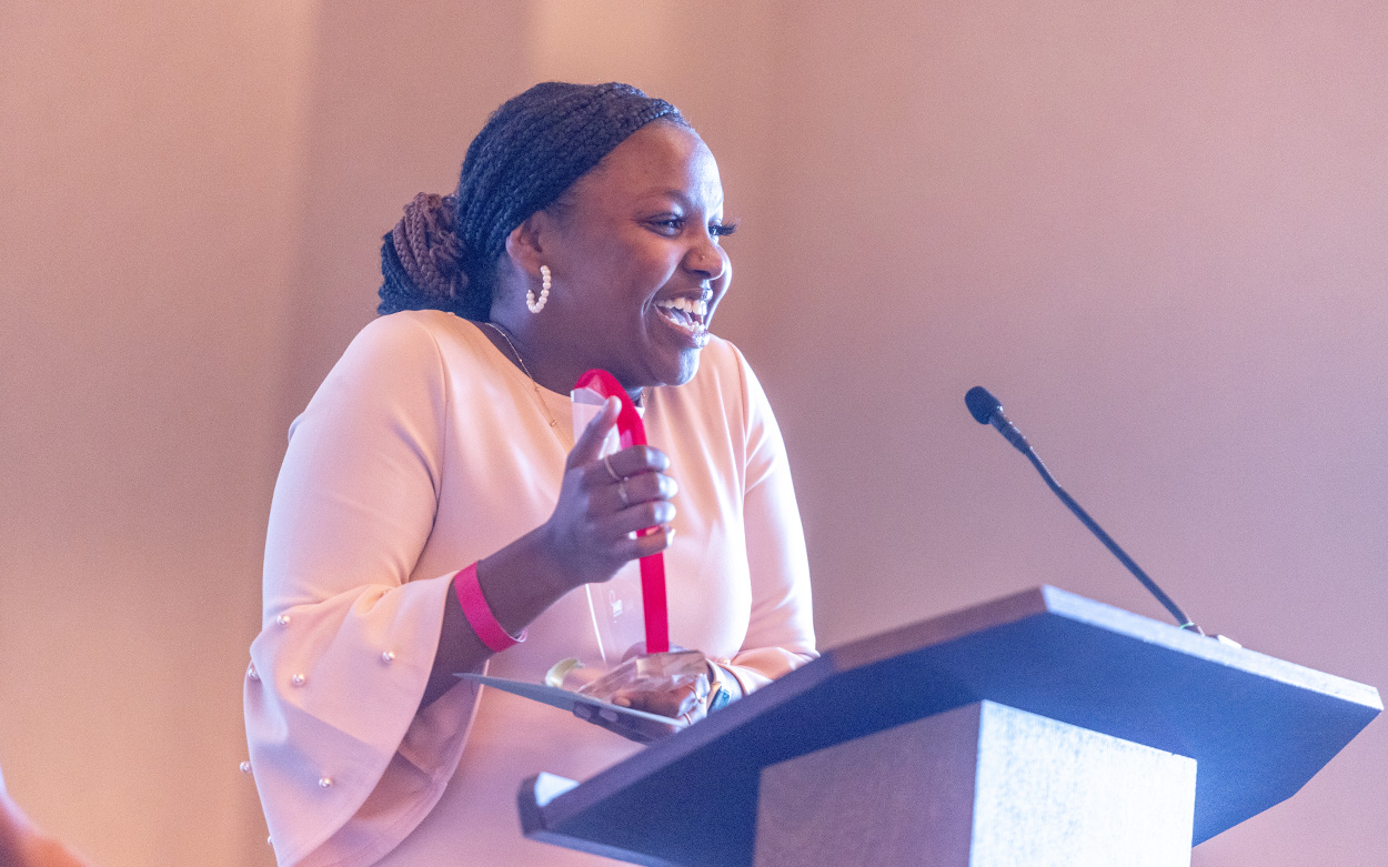 A student smiles and holds up her award