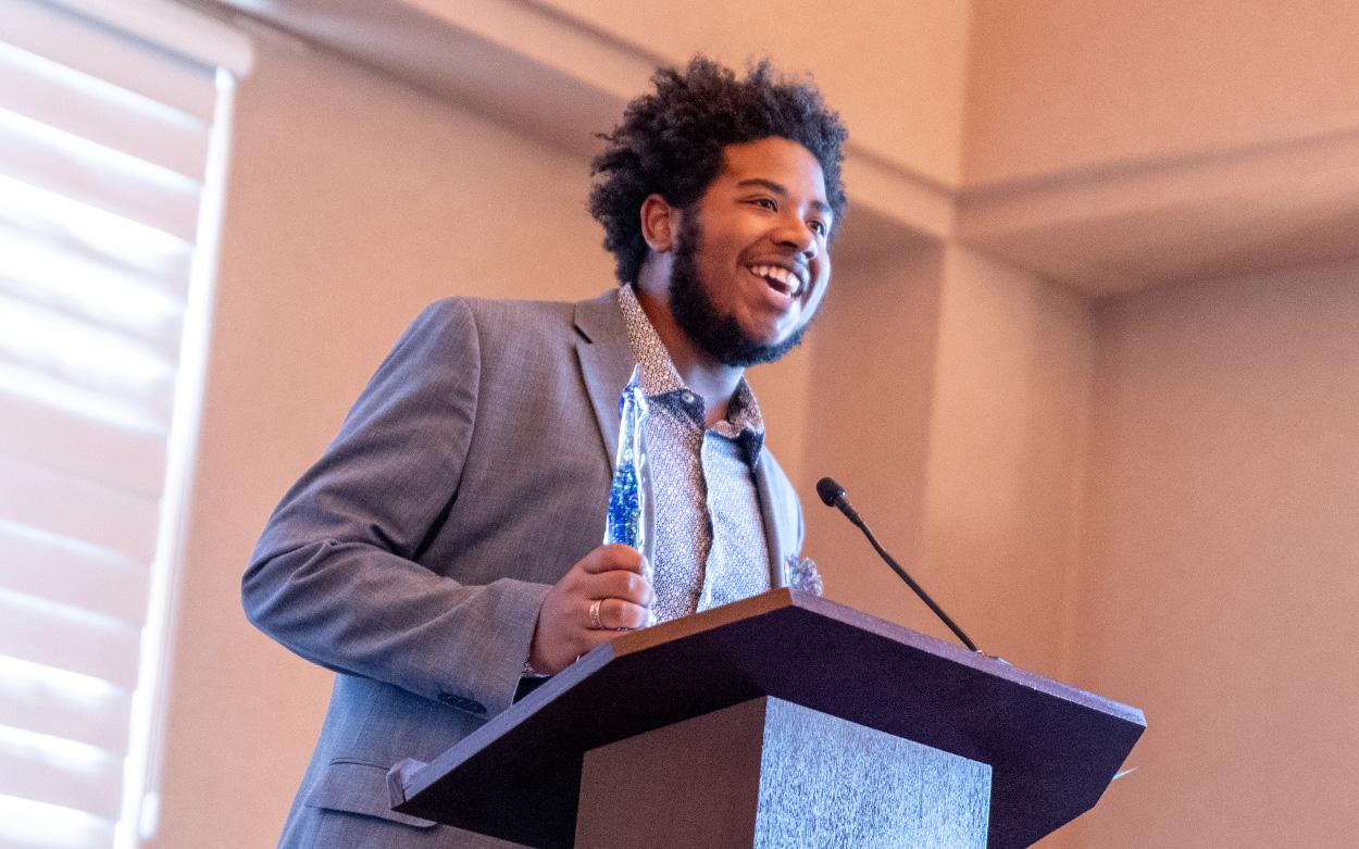 A student smiles while speaking from a podium after receiving an award