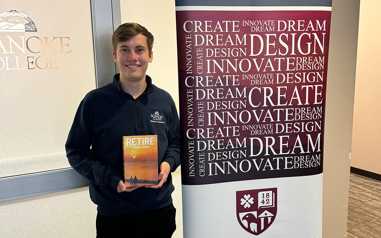 Student smiling while holding a board game mockup next to a sign for the Center for Leadership and Entrepreneurial Innovation