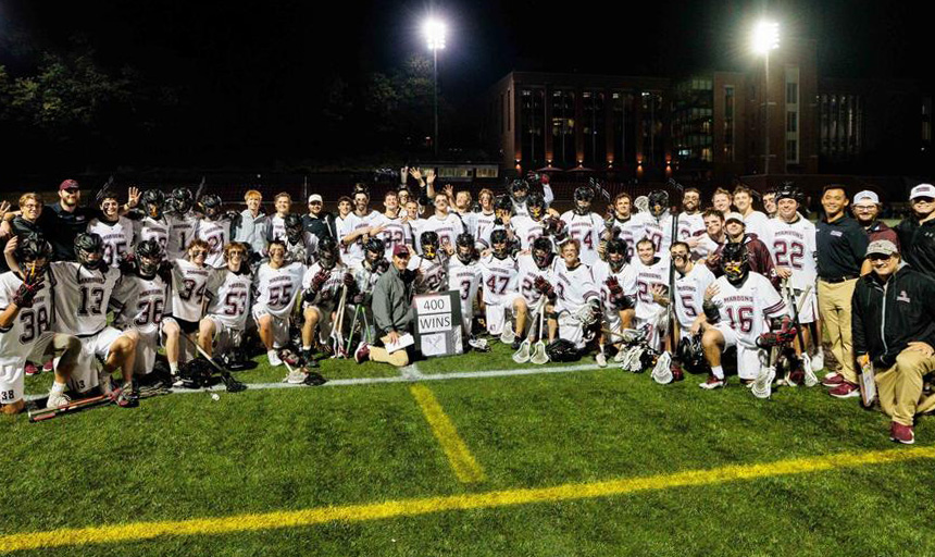 Coaches and players join Coach Pilat for a photo with a sign that reads: 400 WINS