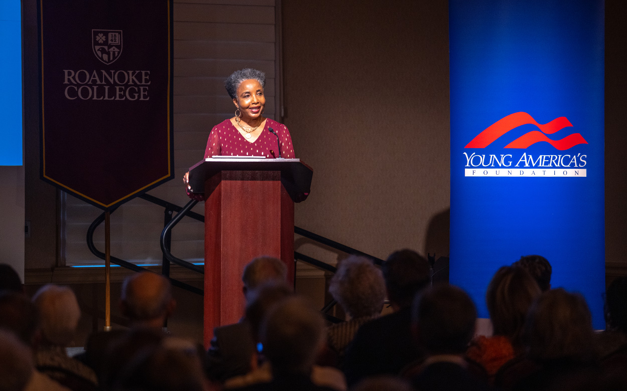 Carol Swain speaks at a podium in Wortmann Ballroom flanked by one banner that reads Roanoke College and a second banner that reads Young America's Foundation