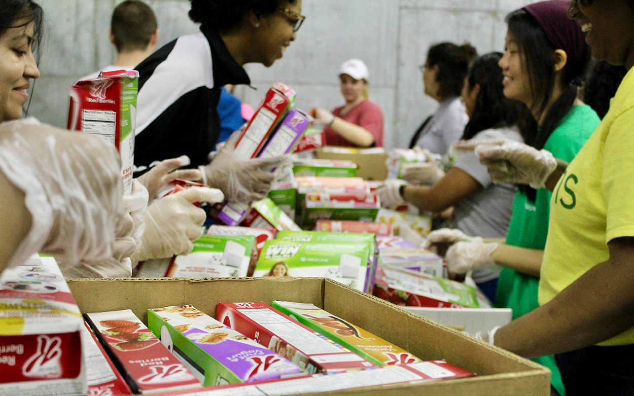 Student workers handling cereal and other boxed food items.