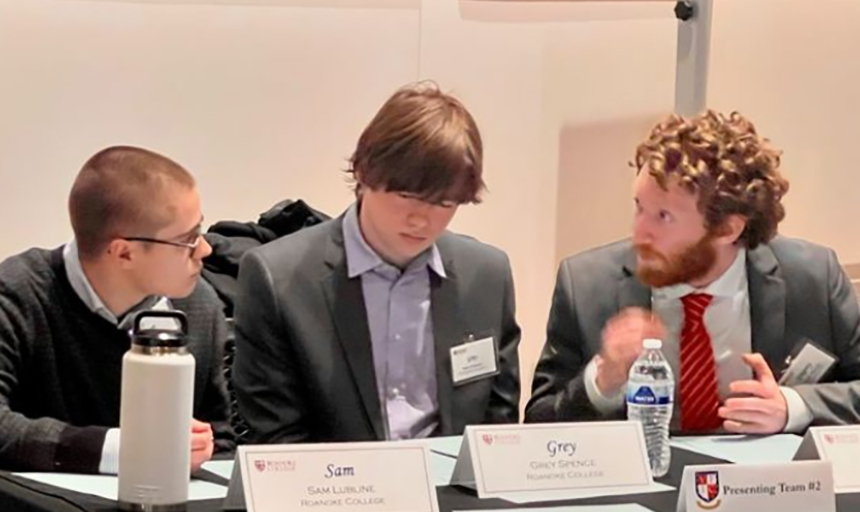 Three students talk while sitting at a table