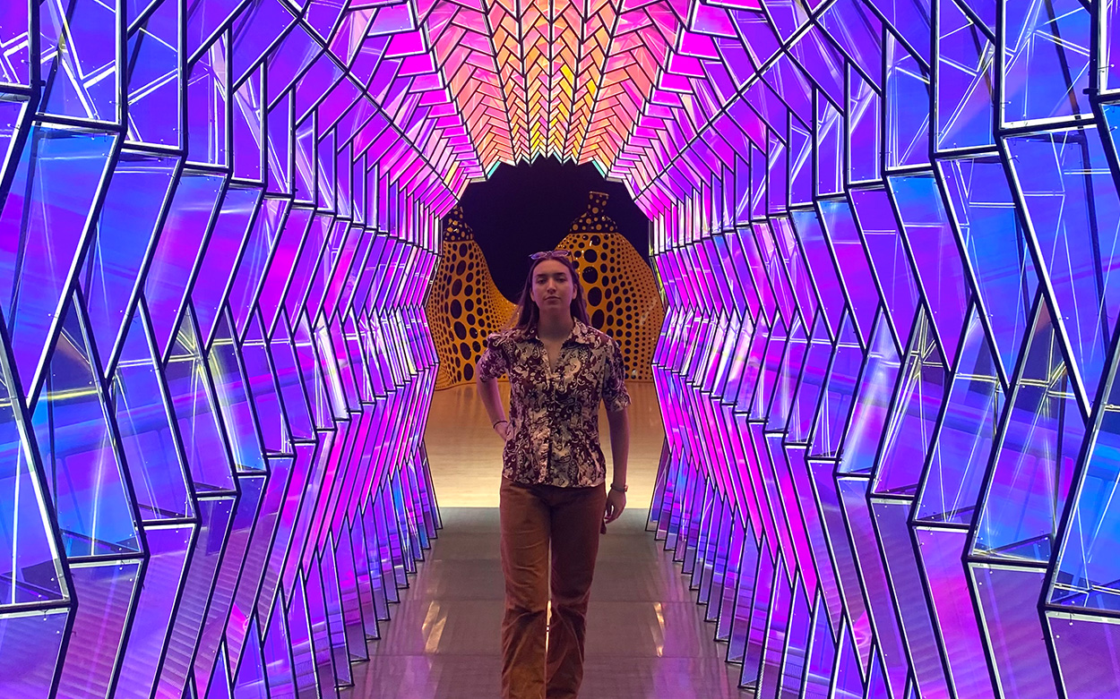 Kendall Donna walking down a hall lined by multi-colored prisms