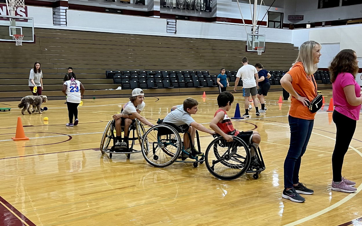 Three children in wheelchairs playing in a Roanoke College gym