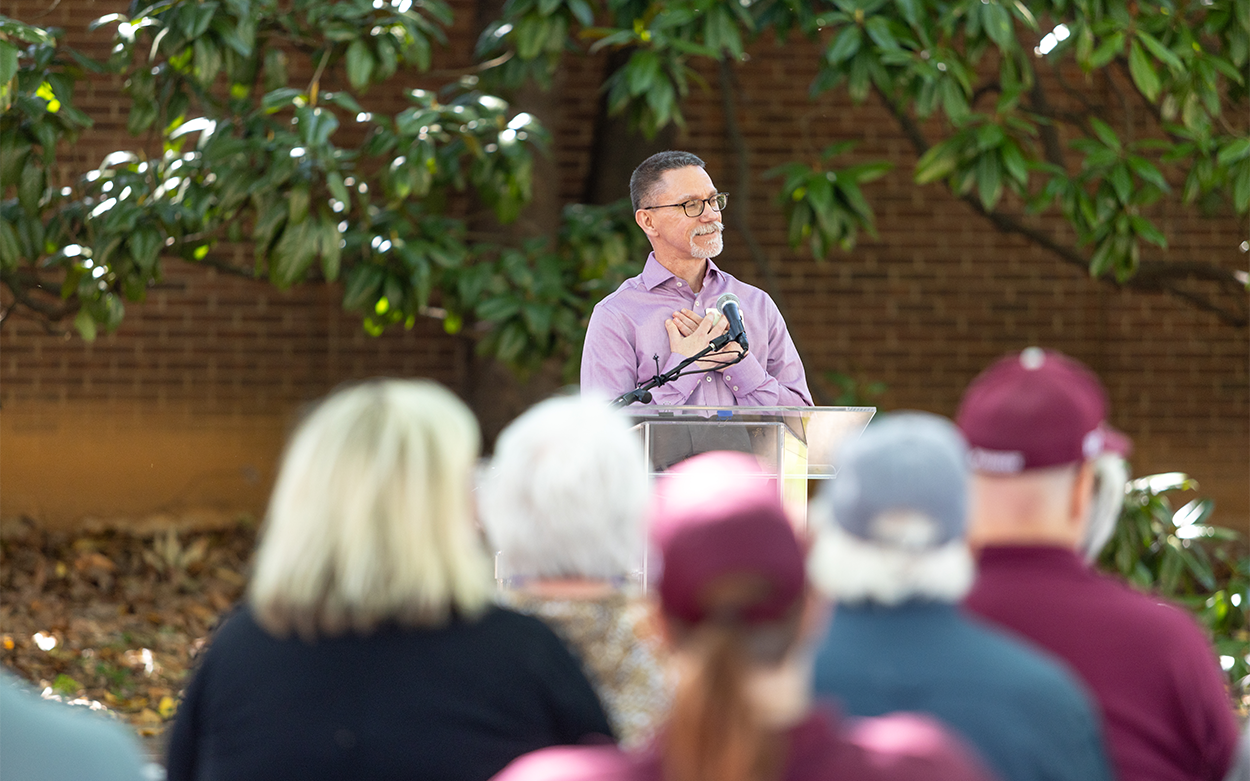 Biology Professor Lens Pysh clasps his hands to his heart while speaking at the ceremony