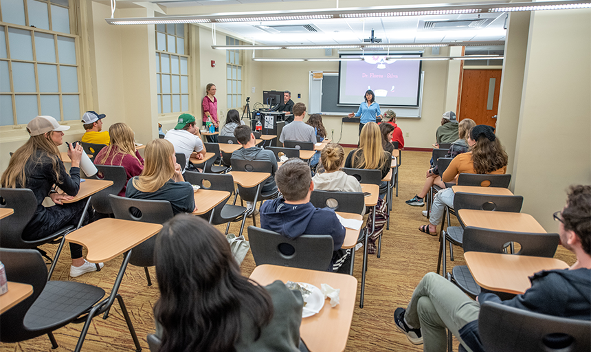 Image of a classroom with several students and professor at the front of the room