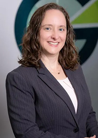 Headshot of a dark-haired woman in a navy blue blazer.