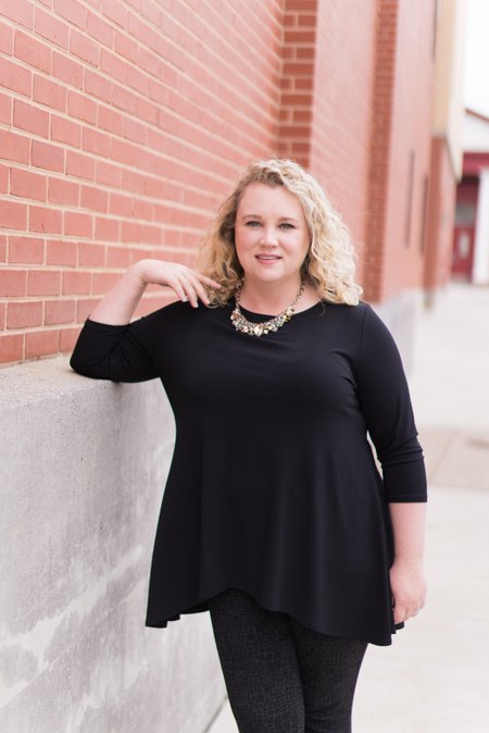 Blonde woman in a black dress poses for a headshot