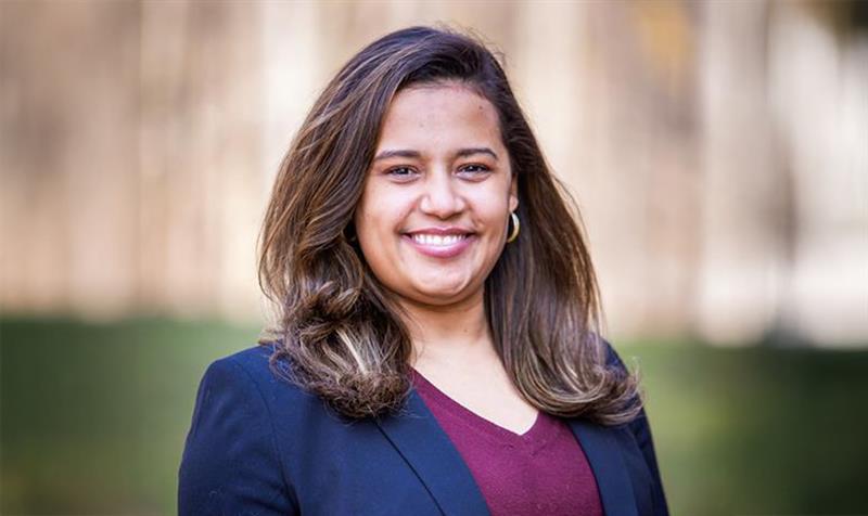Headshot of dark haired woman in raspberry colored blouse and navy blazer.