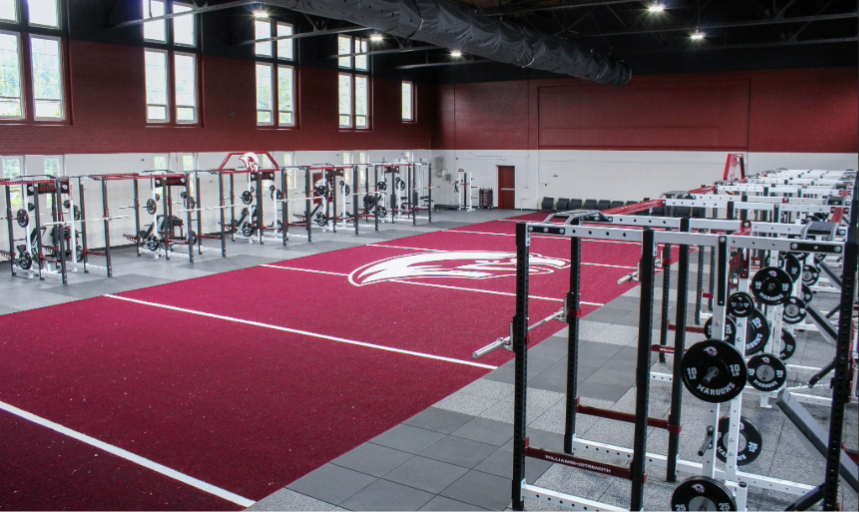 Rows of weight racks and custom maroon turf in the Athletic Performance Center