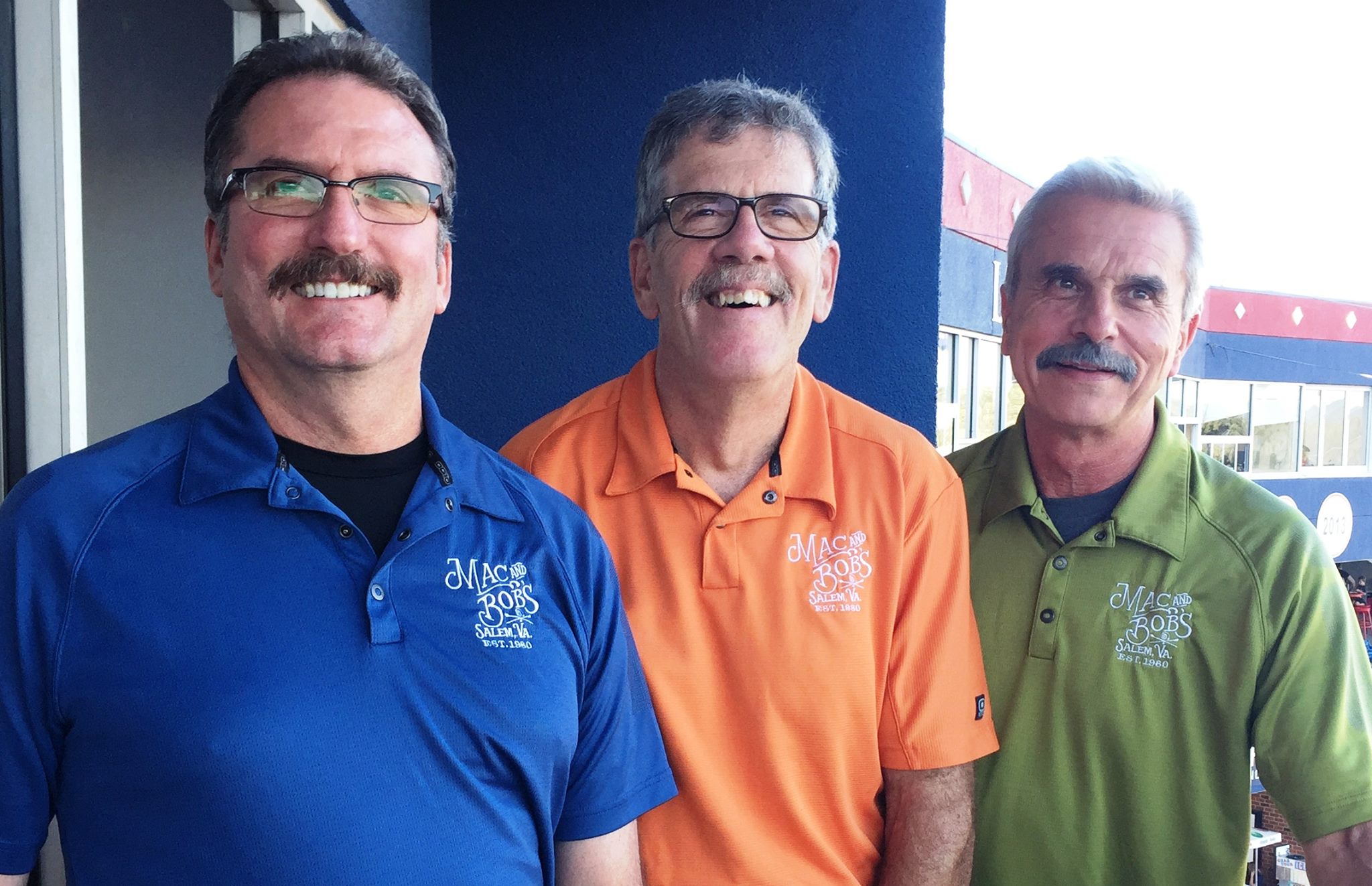 Three men standing in bright colored shirts