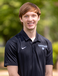 Headshot of young man in a black polo shirt with "Roanoke College Volleyball" embroidered on it.