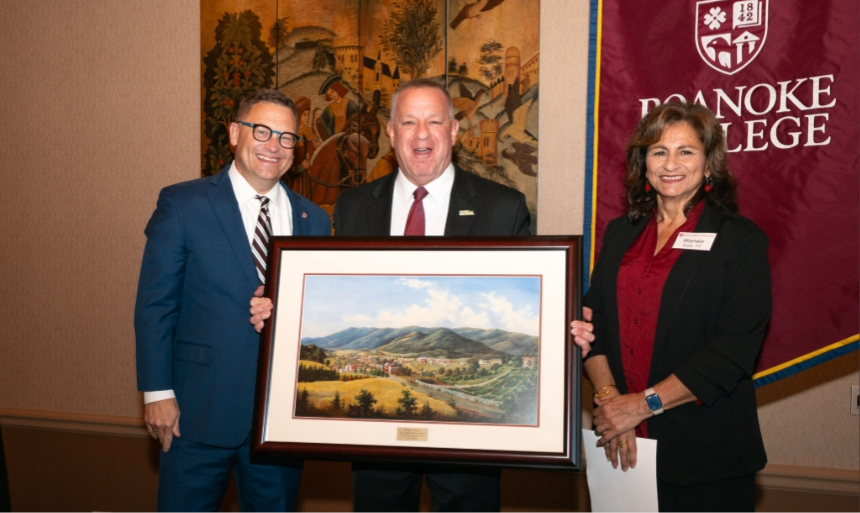Two men and a woman pose with a framed painting of Salem, Va.