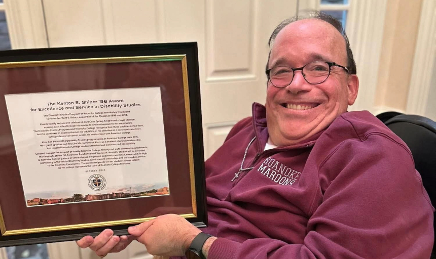 Kent Shiner wears a Roanoke College sweatshirt and holds up a framed copy of the scholarship named after him.