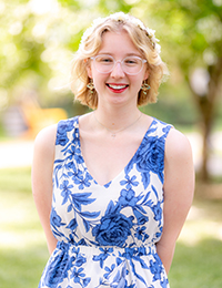 Headshot of young lady wearing a blue-and white print dress with a white flower crown on her head