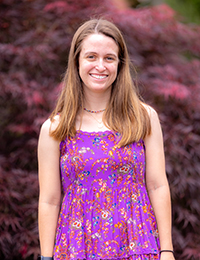 Headshot of young woman in bright purplish pink dress with flowers