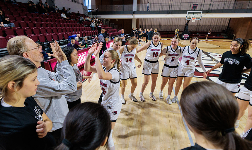 A basketball player high fives a coach