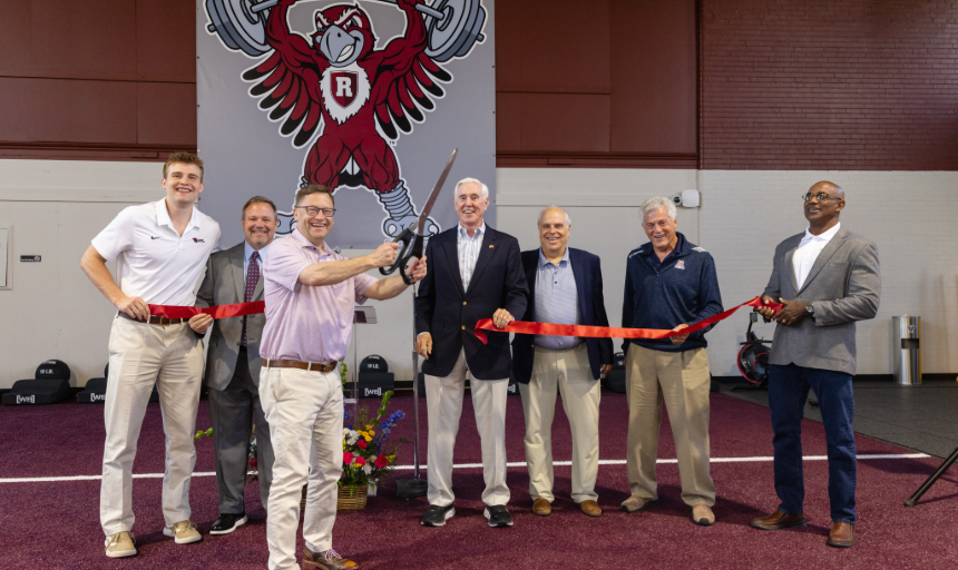 Group of men holding a ribbon while President Shushok cuts the ribbon